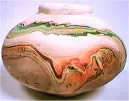 Indian like Nemadji white pot with multi-colored swirl designs in greens, browns, and reds.